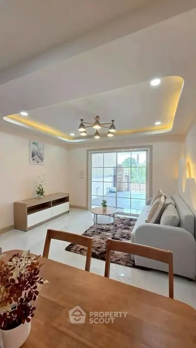 Modern living room with stylish lighting and cozy seating area, featuring a large window for natural light.