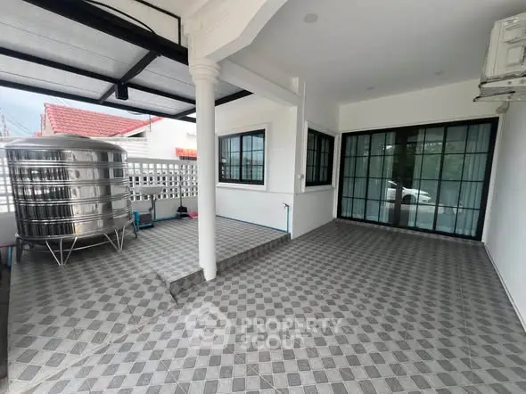 Spacious tiled outdoor area with stainless steel water tank and sliding glass doors.