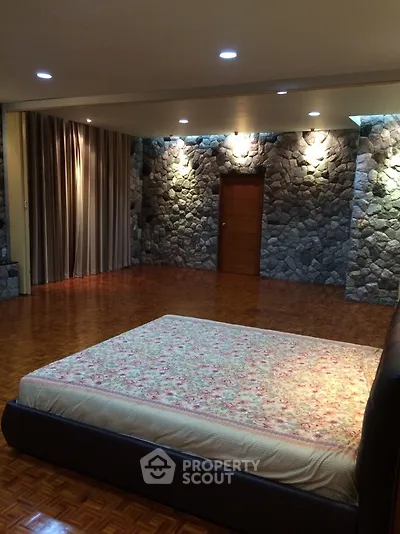 Spacious bedroom with stone accent walls and wooden flooring