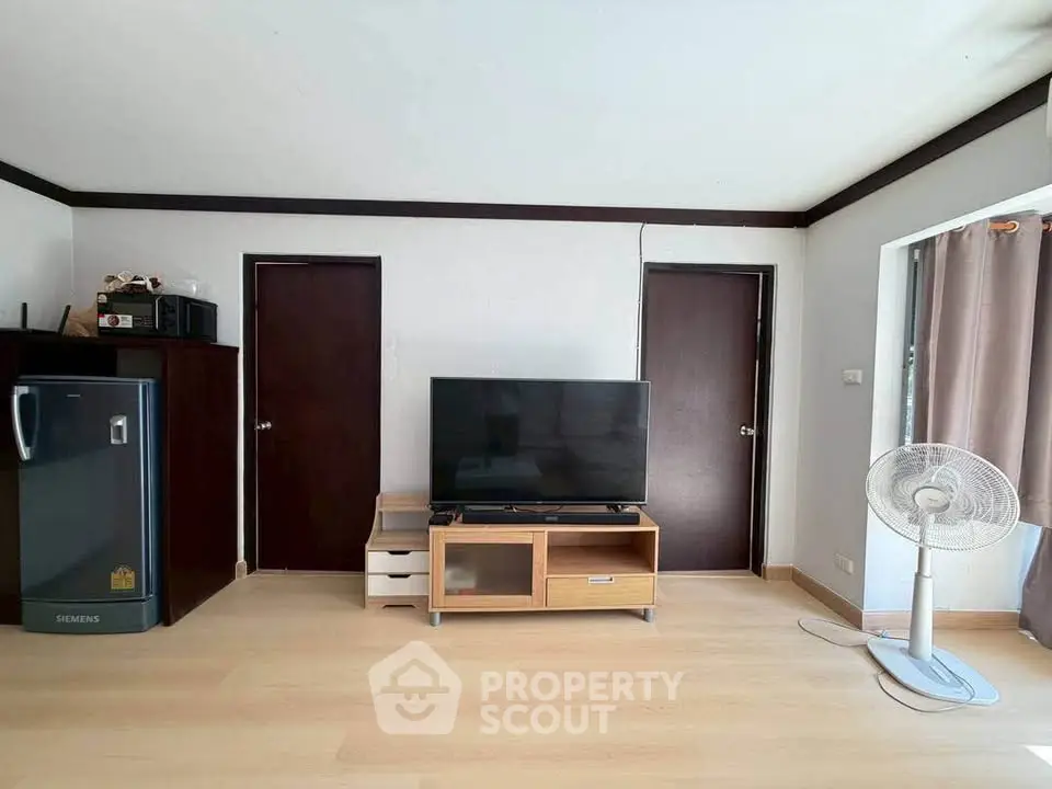 Spacious living room with modern TV setup and sleek wooden flooring