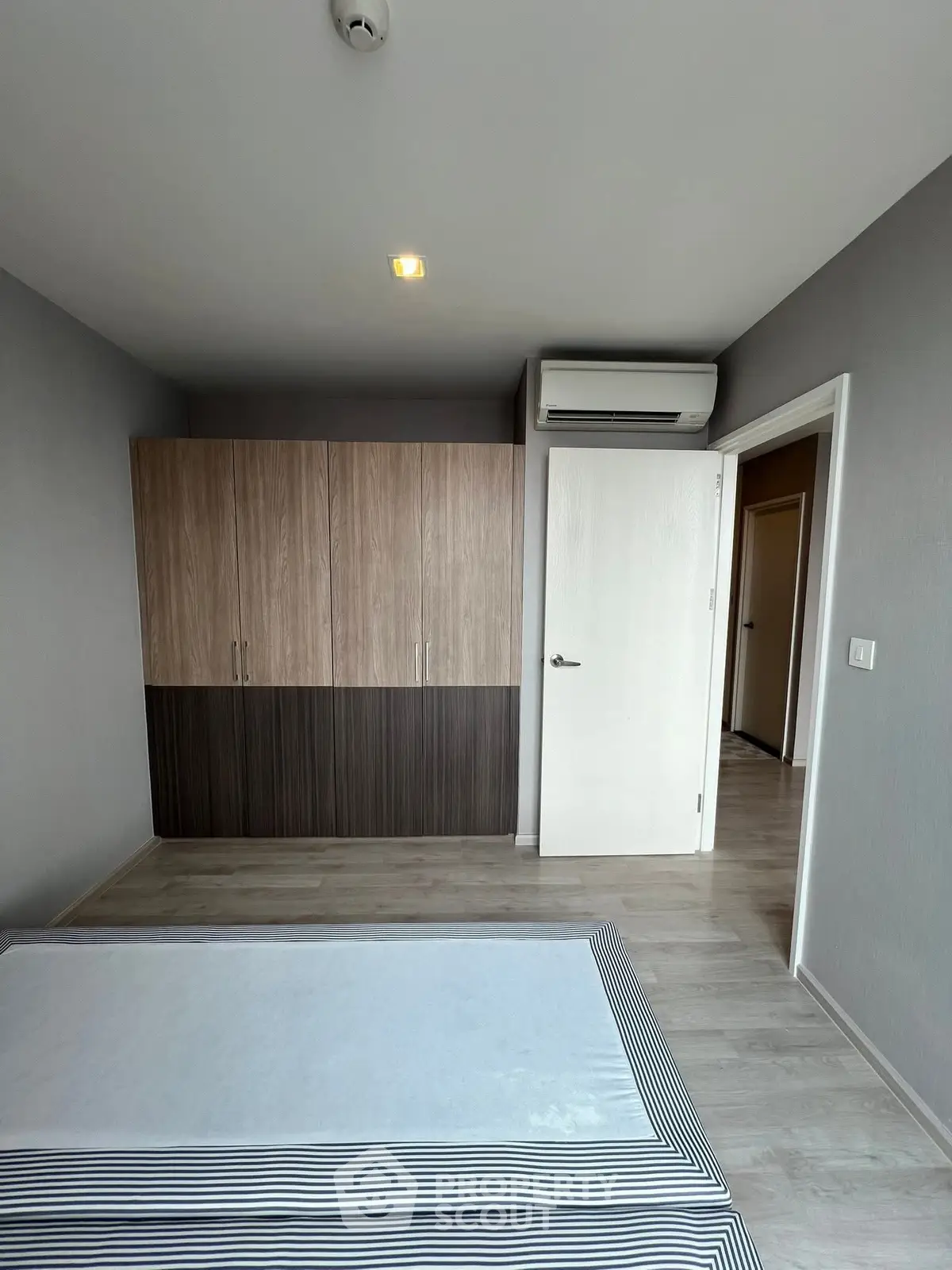 Modern bedroom with sleek wardrobe and air conditioning in a stylish apartment.