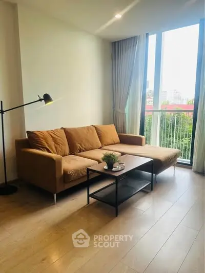 Modern living room with stylish sofa and floor lamp, featuring large windows and wooden flooring.
