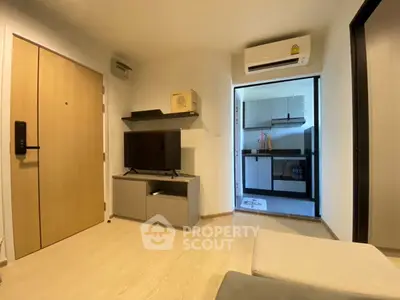Modern living room with TV and air conditioning next to a compact kitchen.