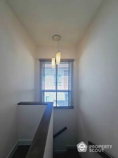 Bright stairway with modern pendant lighting and window view