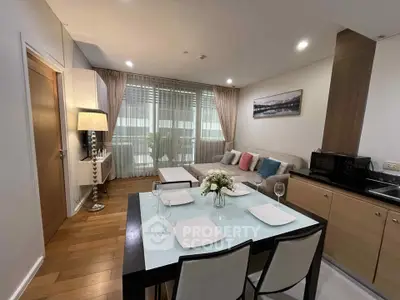 Modern living room with dining area, featuring elegant decor and natural light from large windows.