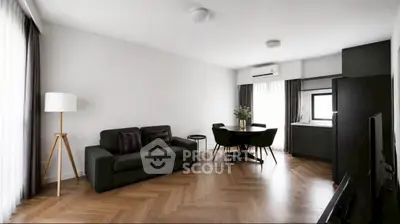 Modern living room with sleek black furniture and open kitchen layout