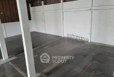 Spacious industrial warehouse with high ceilings and white brick walls.