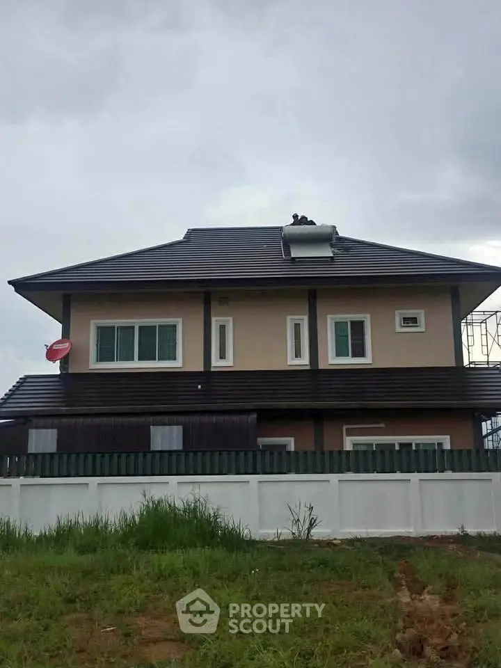 Elegant two-story house with modern roof and fenced yard, perfect for family living.