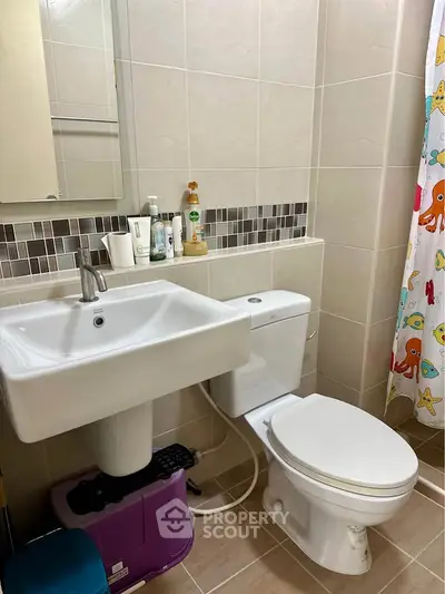 Modern bathroom with stylish sink and toilet, featuring colorful shower curtain.