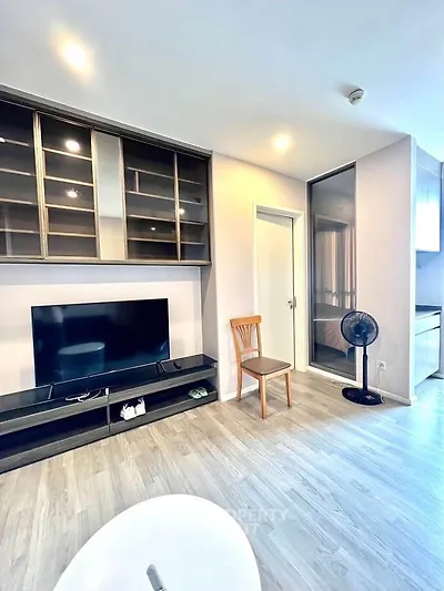 Modern living room with sleek TV unit and glass cabinet, featuring light wood flooring and contemporary decor.