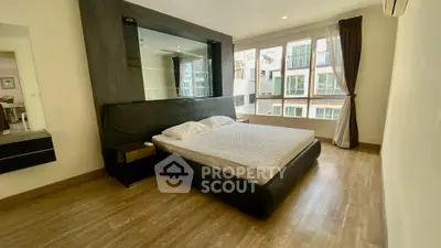 Spacious bedroom with modern design and large windows offering natural light in a stylish apartment.