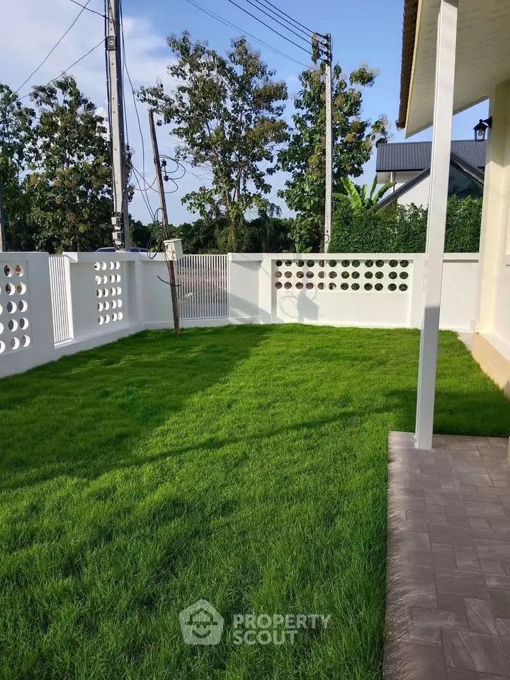 Charming garden area with lush green lawn and modern fence, perfect for outdoor relaxation.