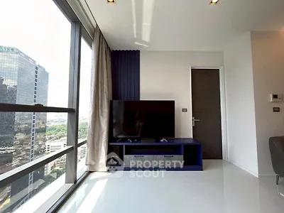 Modern living room with large windows and city view, featuring sleek TV setup.