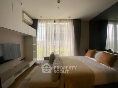 Modern bedroom with large windows and cozy sofa in stylish apartment