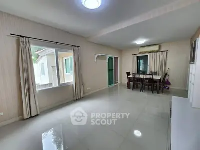 Spacious dining area with large windows and modern decor in a bright home.