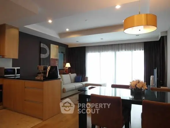 Modern open-plan living room with stylish kitchen and dining area, featuring elegant lighting and contemporary decor.