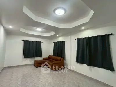 Spacious living room with modern ceiling design and cozy brown sofa, perfect for relaxation.