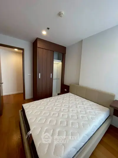 Modern bedroom with wooden flooring and sleek wardrobe design.