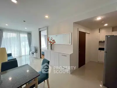Modern open-plan living room with dining area and sleek kitchen in a bright apartment.