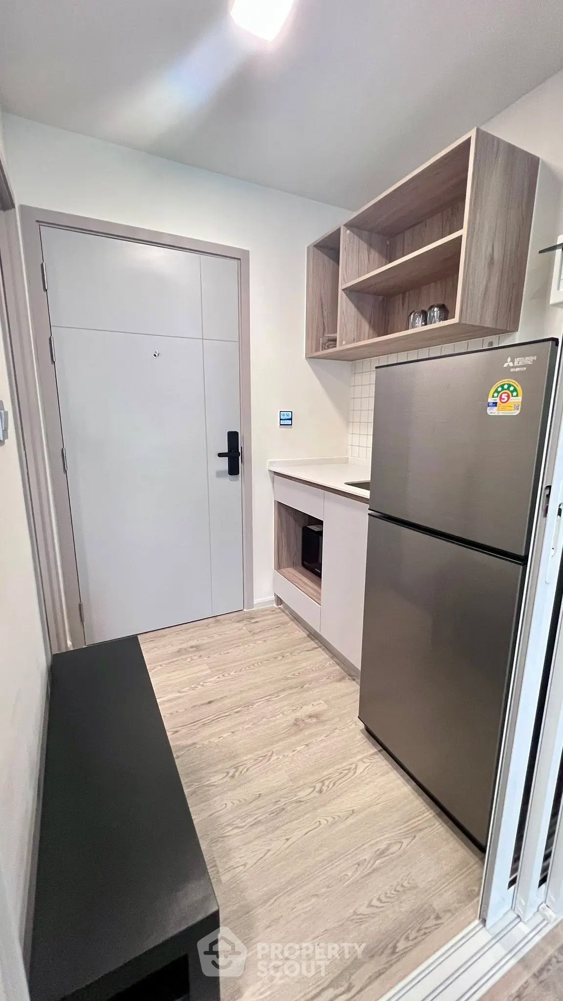 Compact kitchen with modern fridge and wooden cabinetry in cozy apartment