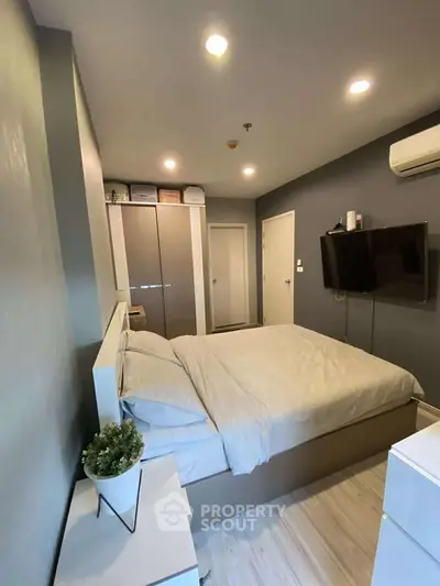 Modern bedroom with sleek design, featuring a wall-mounted TV and ample storage space.