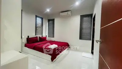 Modern bedroom with red bedding and sleek design, featuring air conditioning and minimalist decor.