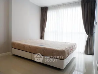 Spacious bedroom with large window and elegant curtains, perfect for natural light lovers.