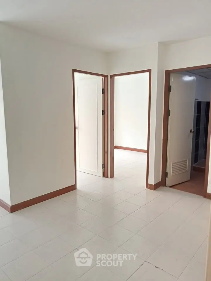 Spacious interior with white tiled flooring and multiple doorways in a modern apartment.