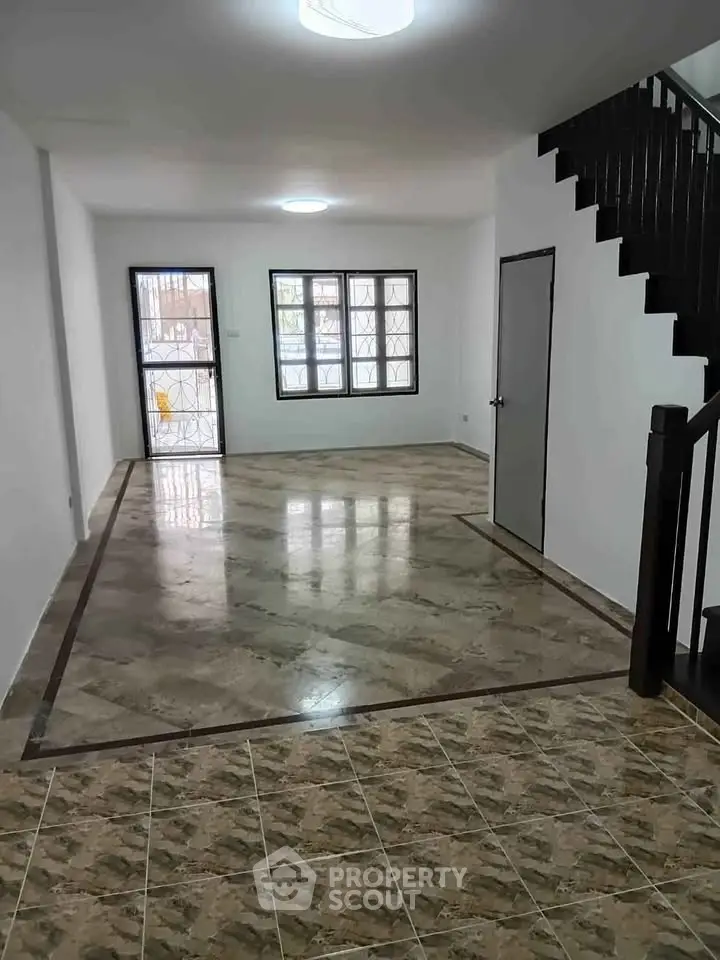 Spacious living room with elegant tiled flooring and staircase, perfect for modern family living.