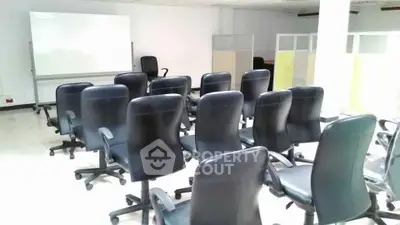 Spacious office space with multiple chairs and a whiteboard, ideal for meetings or training sessions.