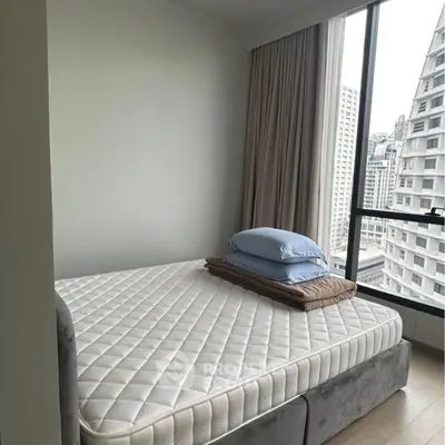 Modern bedroom with large window offering city view and cozy bedding.