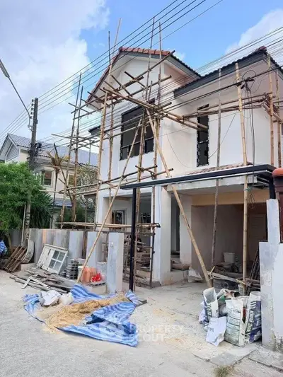 Under-construction house with scaffolding and building materials, showcasing potential for customization.