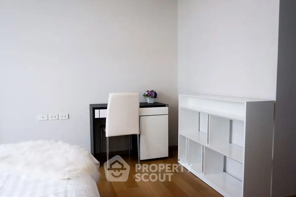 Modern minimalist bedroom with sleek desk and white shelving unit, perfect for a stylish urban lifestyle.