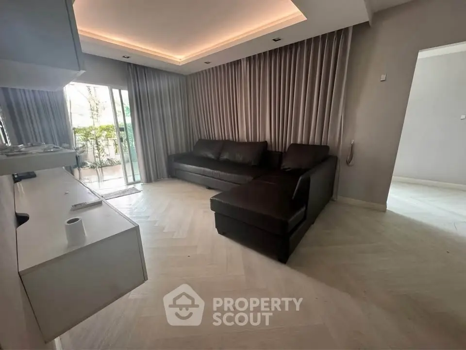 Modern living room with sleek design and large windows opening to a balcony, featuring a stylish L-shaped sofa.