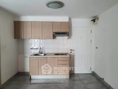 Compact kitchen with modern cabinetry and tiled backsplash in a cozy apartment setting.