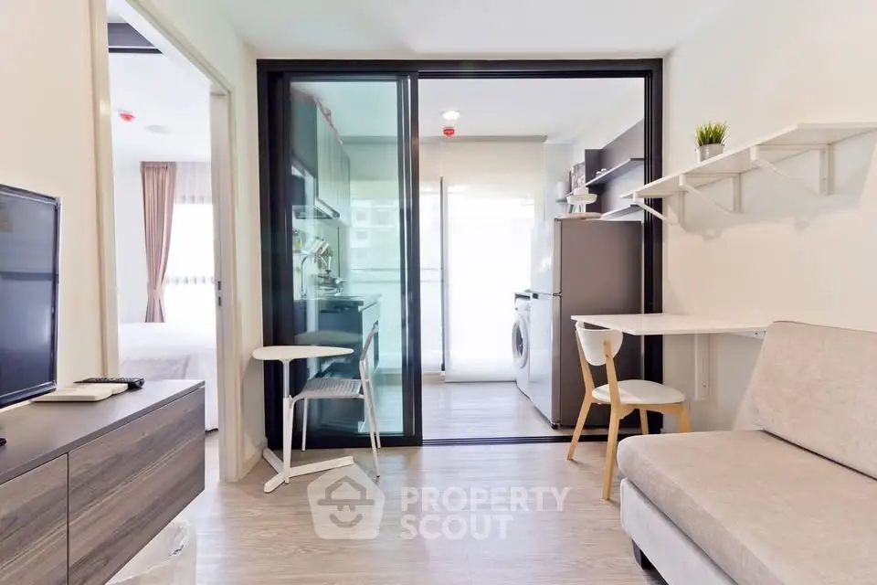 Modern apartment interior with open layout, featuring a cozy living area and compact kitchen with washing machine.