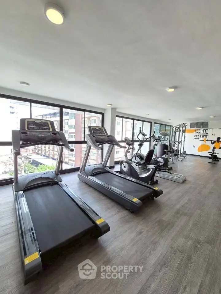 Modern gym with treadmills and exercise equipment in a bright, spacious room with large windows.