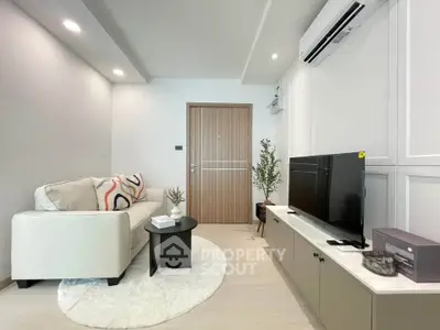 Modern living room with sleek furniture and stylish decor, featuring a cozy sofa and flat-screen TV.