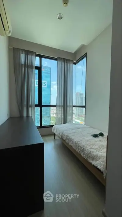 Modern bedroom with large windows offering stunning city views and natural light.