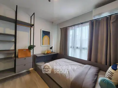 Modern bedroom with stylish decor and ample natural light, featuring a cozy bed and sleek shelving.
