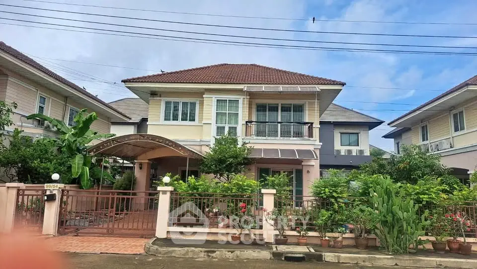 Charming two-story house with lush garden and gated entrance in a serene neighborhood.