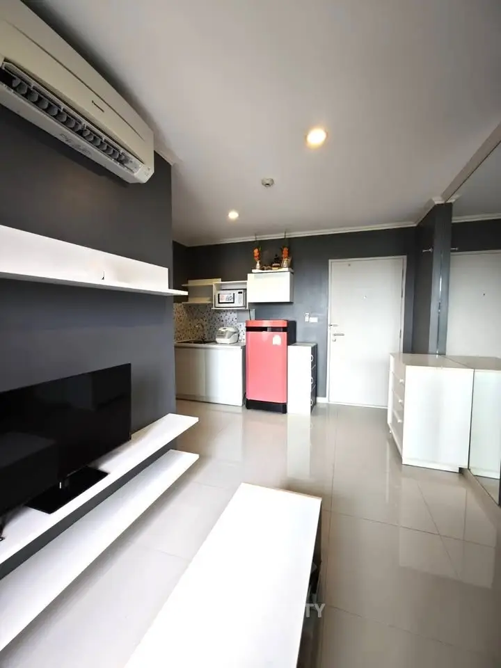 Modern living room with sleek design, featuring a compact kitchen and stylish decor.