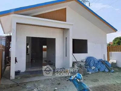 Modern single-story house under construction with blue roof and open entrance.
