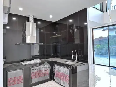 Modern kitchen with sleek black cabinetry and stainless steel appliances in a spacious open layout.