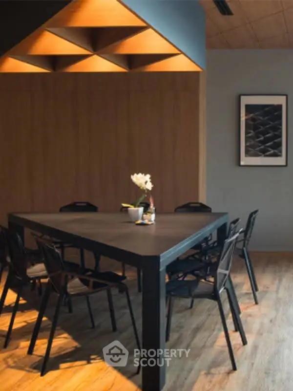 Modern dining area with sleek black table and chairs, warm lighting, and stylish decor.