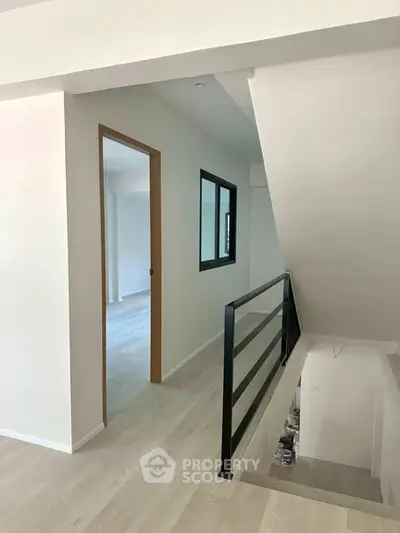 Modern interior hallway with sleek railing and light wood flooring