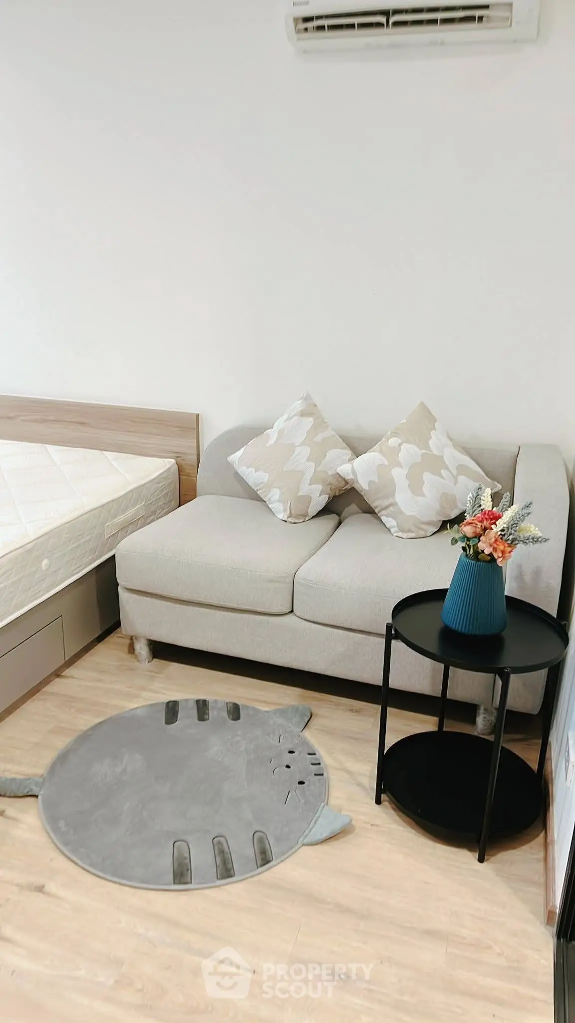 Cozy bedroom with stylish sofa, decorative rug, and air conditioning