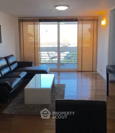 Modern living room with sleek black leather sofa and large window view.
