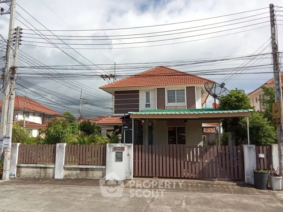 Charming two-story house with red roof and fenced yard in suburban neighborhood.