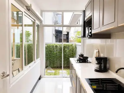 Modern kitchen with sleek cabinetry and garden view, featuring gas stove and coffee maker.